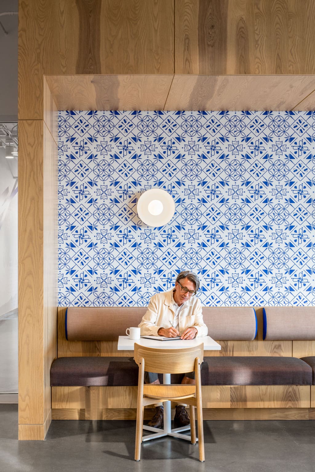 A man works at a booth featuring Live Sawn Bright Ash Veneer Paneling banquettes and millwork