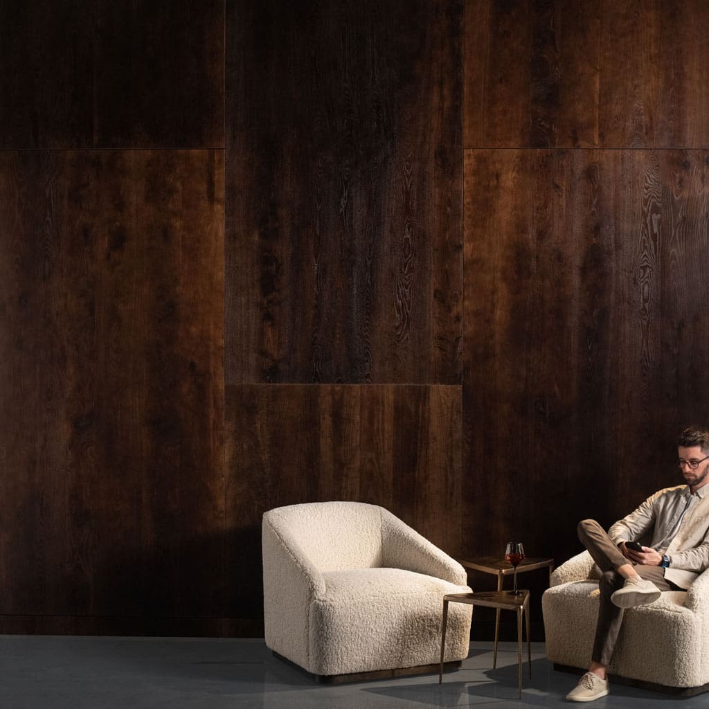 Man sitting in front of Live Sawn Dark Ash Wood Veneer Paneling in Deep Brown feature wall