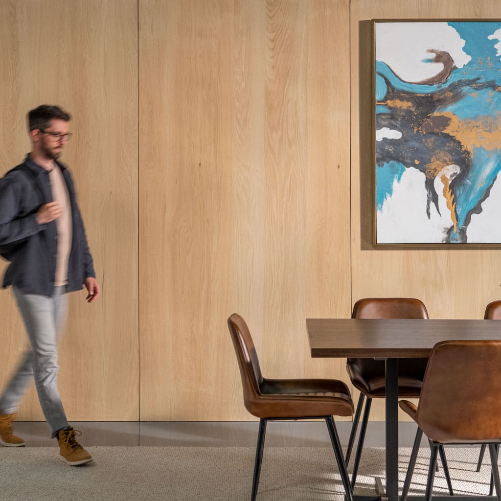Student walking to a table in front of Live Sawn Red Oak Veneer Wood Wall Paneling