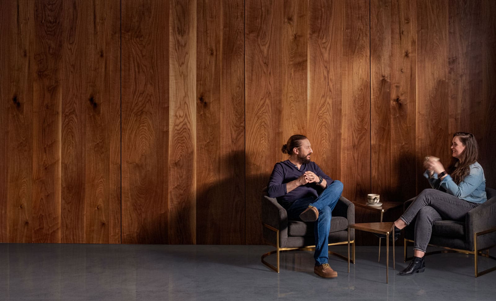 Two people drink coffee in front of Live Sawn Walnut Veneer Paneling wall installation
