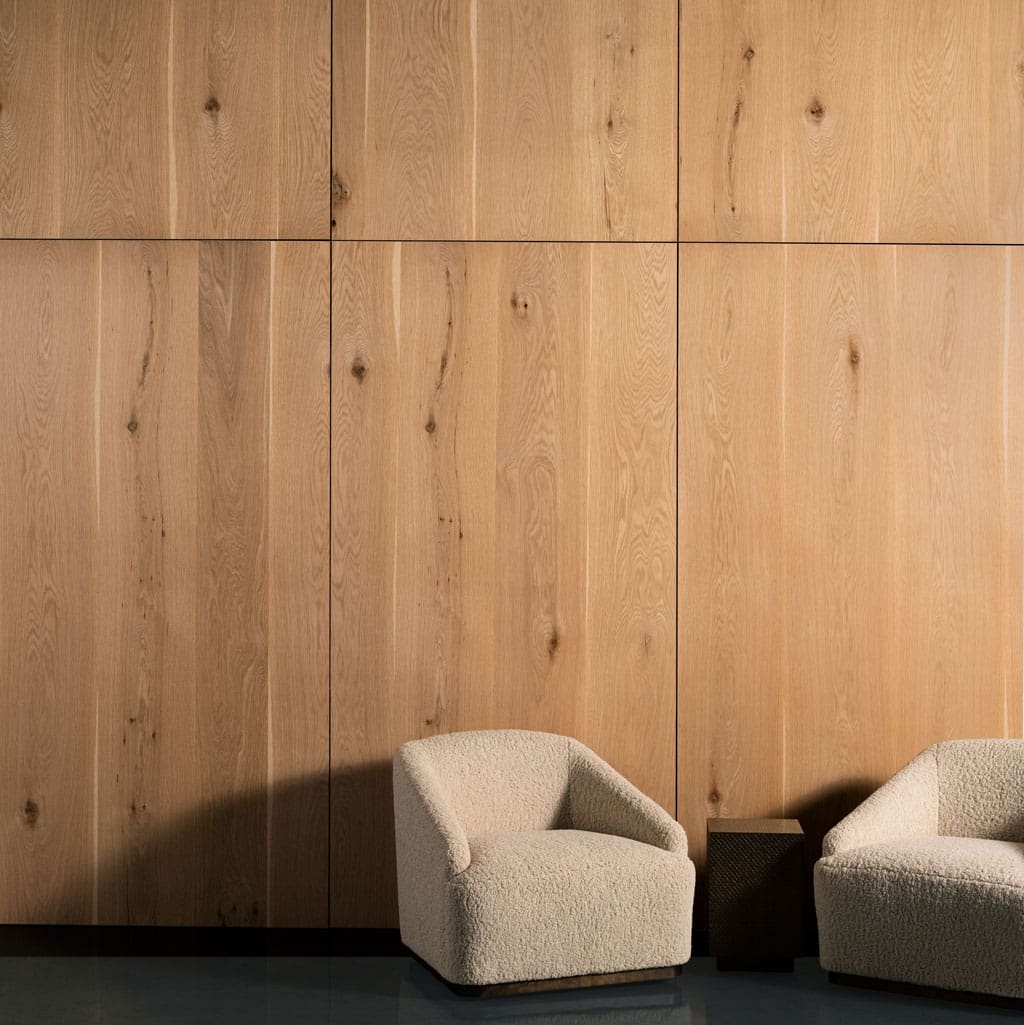 Two white chairs in front of Live Sawn White Oak Wood Veneer Paneling feature walls